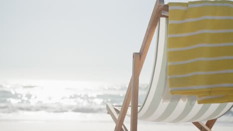Close-up-of-deck-chair-and-towel-on-beach,-in-slow-motion,-with-copy-space