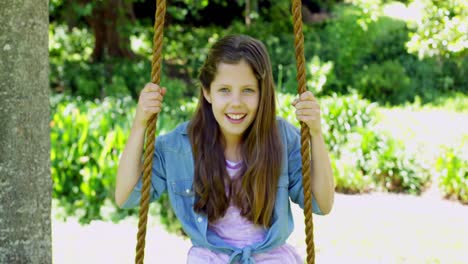 cute little girl sitting on a swing in the park