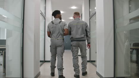 two workers walking in an office hallway