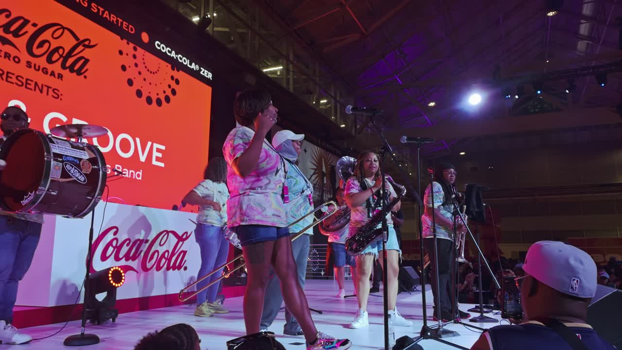 Panning shot of musician on stage wt Essence Festival in Atlanta City. Group of dark-skinned people in stadium.