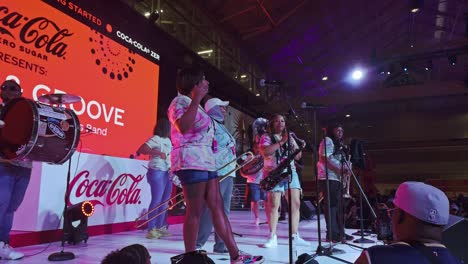 panning shot of musician on stage wt essence festival in atlanta city. group of dark-skinned people in stadium.
