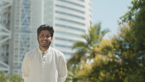 portrait of young muslim man smiling at camera on sunny day.