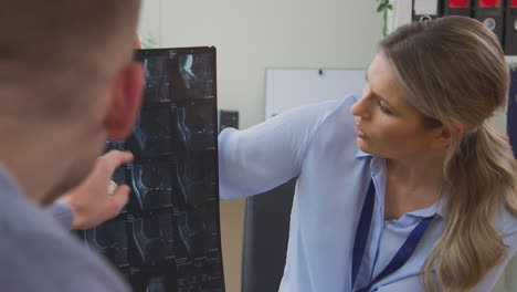 Doctora-O-Médico-De-Cabecera-En-El-Consultorio-Con-Un-Paciente-Masculino-Mirando-Una-Tomografía-Computarizada-O-Una-Resonancia-Magnética