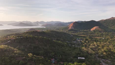 drone view of coron town, philippines during sunset with scattered islands, calm sea, forested hills, and boats gliding through the golden waters