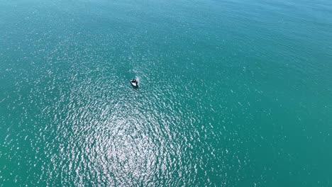 órbita-Aérea,-Día-Soleado-De-Un-Solo-Barco-En-Medio-De-Un-Gran-Océano-Azul