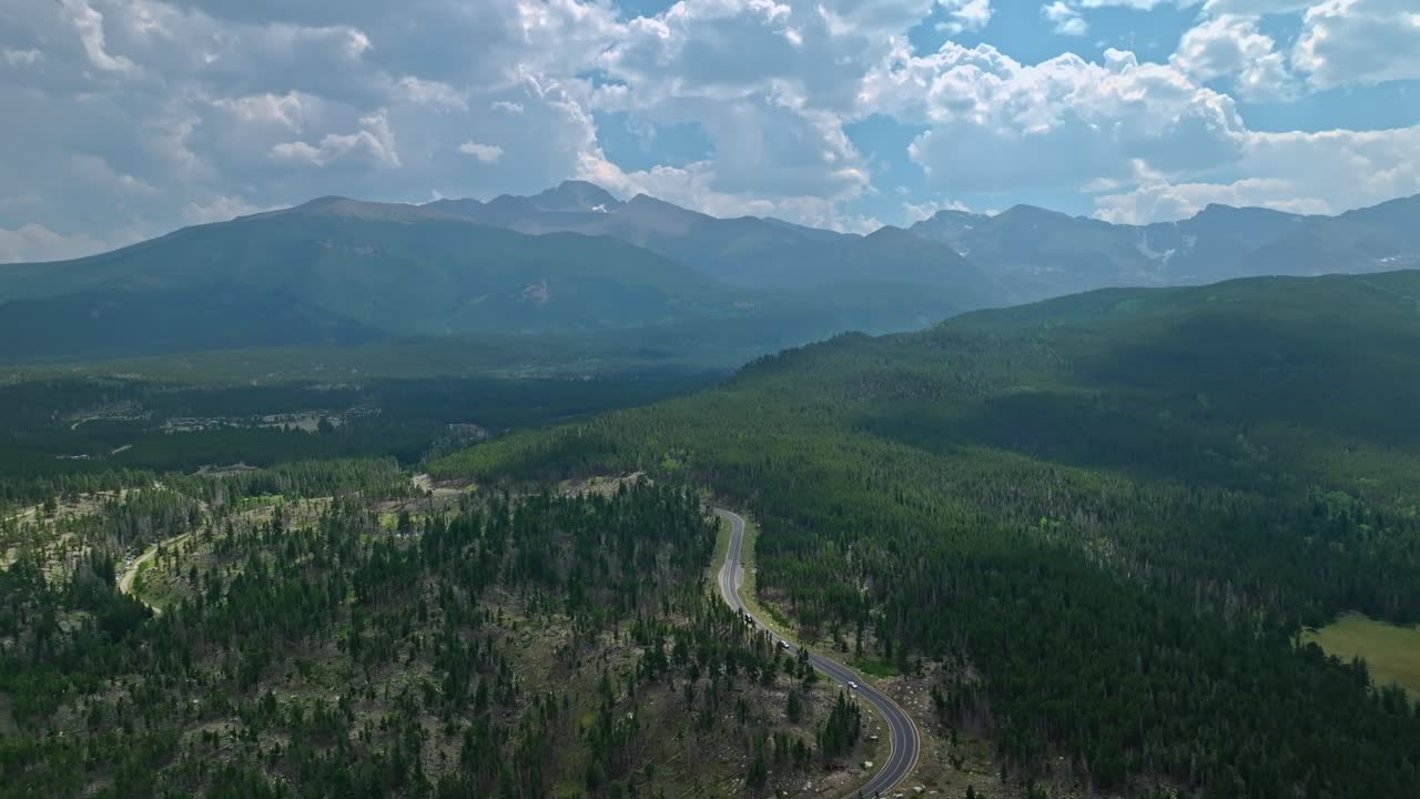 fotografía aérea de valles verdes y colinas boscosas con picos de montañas distantes bajo un cielo nublado