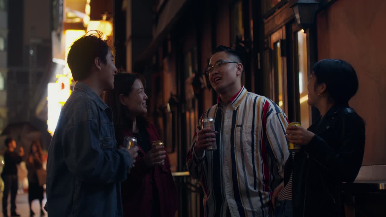 Friends enjoying drinks in a city street at night