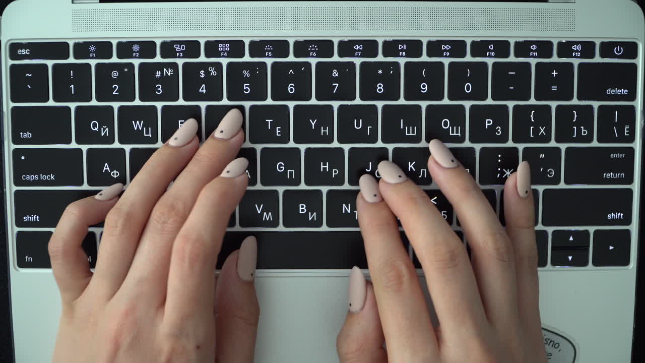 Female hands press keys on the keyboard of a MacBook with a Russian layout