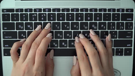 female hands press keys on the keyboard of a macbook with a russian layout