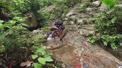 woman on jungle hike uses phone to film low angle closeup waterfall