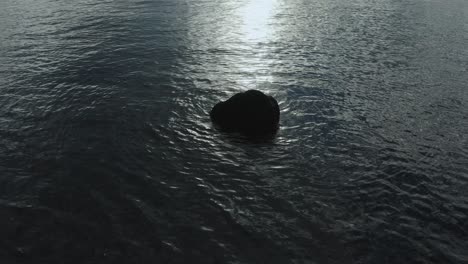 Shot-of-rock-in-the-ocean-silhouetted-in-front-of-morning-sun