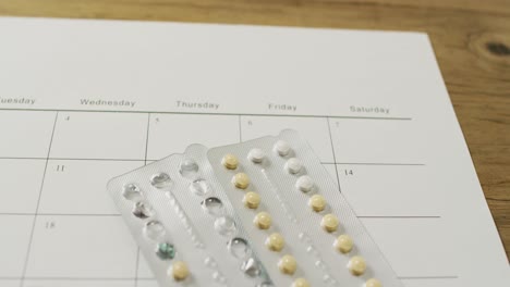 video of close up of yellow tablets over calendar on wooden table