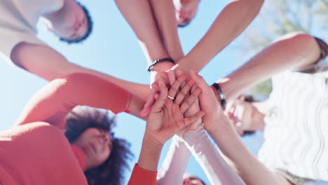 group of people stacking hands together to symbolize teamwork and collaboration