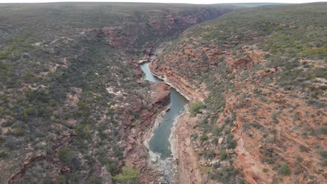 drohnenflugzeug bewegt sich rückwärts über einer australischen schlucht und einem nationalpark mit einem fließenden fluss an einem sonnigen tag