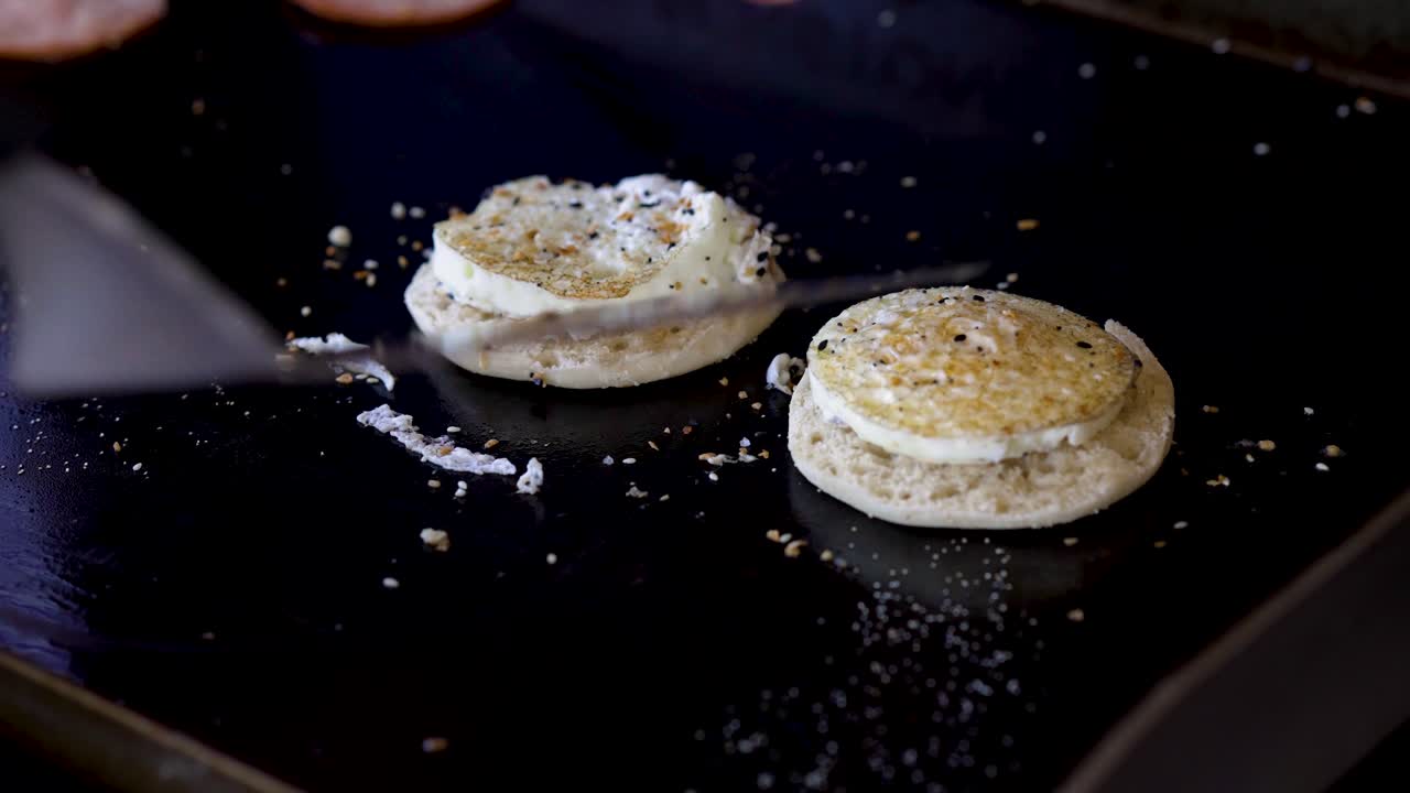 Breakfast sandwich being put together on a hot cast iron griddle