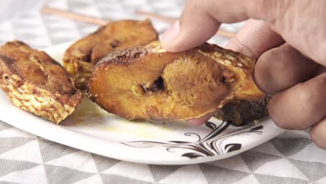 hand picking fried fish on a plate