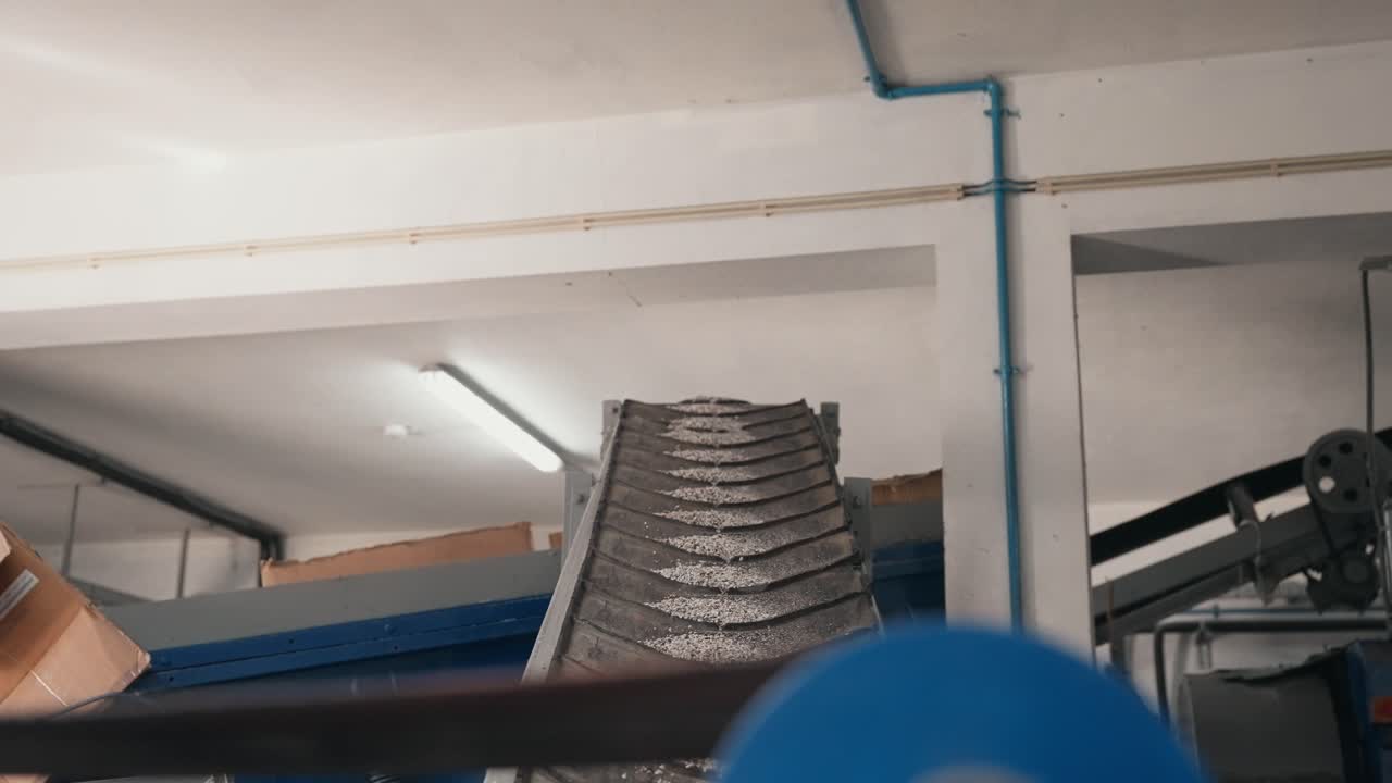 Rubber granulate transported upward on conveyor inside recycling facility