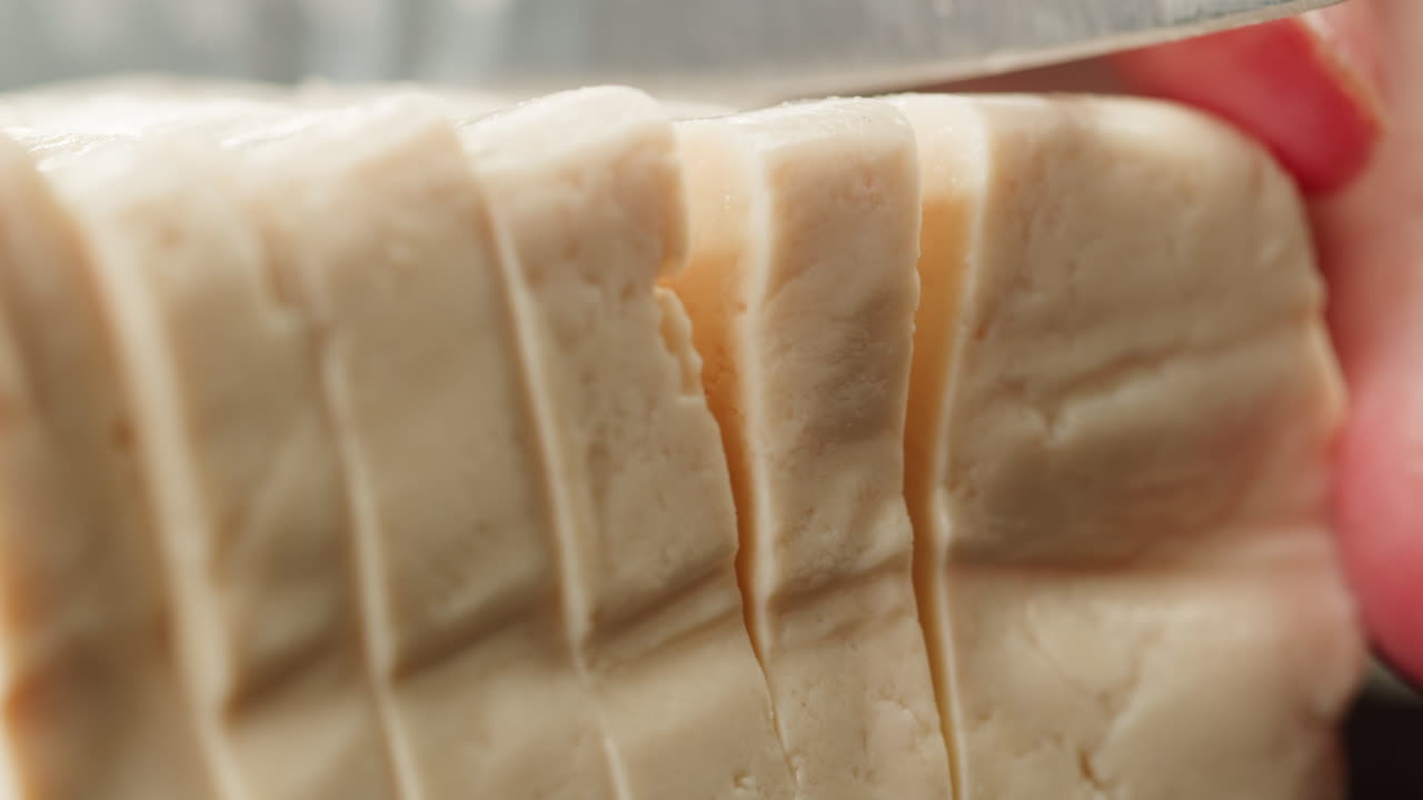 Chef cut cheese for Fried tofu with sesame seeds and spices on cast iron pan, cooking japanese salad. Healthy ingredient for cooking vegan vegetarian diet food. Roasted tofu over black background.