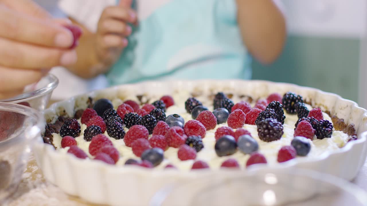 una niña ayudando a su madre a adornar un pastel de bayas