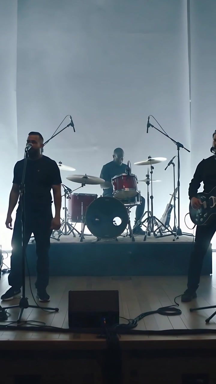 Video verticale: Una band che suona, canta e batte la batteria sul palco, la telecamera zooma per mostrare una batteria rossa.