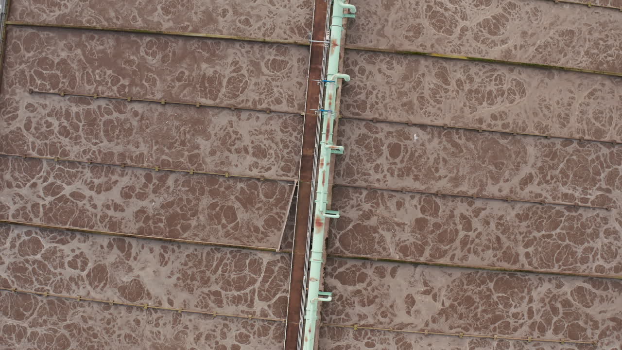 toma aérea que se eleva para revelar una gran planta de procesamiento de aguas residuales simétrica