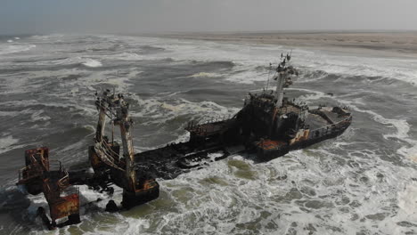 Static-aerial-shot-above-shipwreck-remains---waves-crashing-around