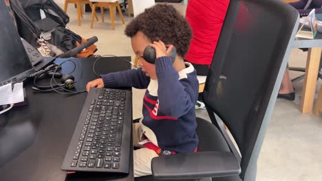 3-year-old black child learns by imitation, typing and making calls at his mother’s office desk
