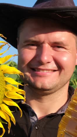 happy farmer holding bottle of oil in sunflowers field happy farmer holding bottle of oil in sunflowers field a young farmer holds a ripe sunflower head in a field
