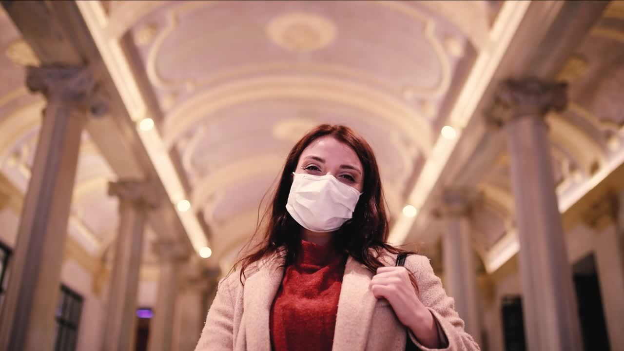 Slow Motion:Beautiful girl wearing protective medical mask and fashionable clothes does thumbs up gesture