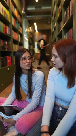 two young women discussing in a library