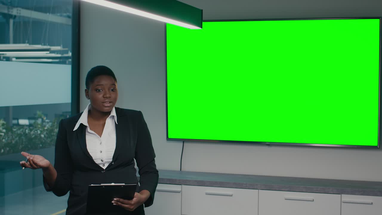 emprendedora negra haciendo una presentación cerca de la pantalla clave de croma verde en la oficina