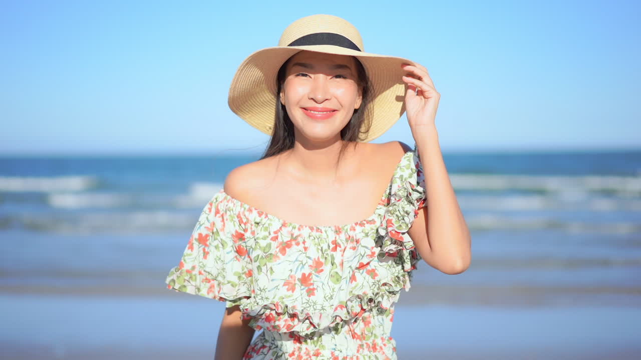 Slow-motion of Asian lady posing for portrait picture on the beach in Thailand wearing a long sundress, blurred background