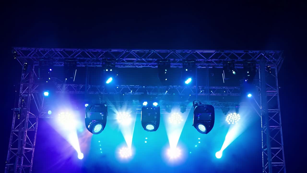 Stage lights illuminate a dark night sky.