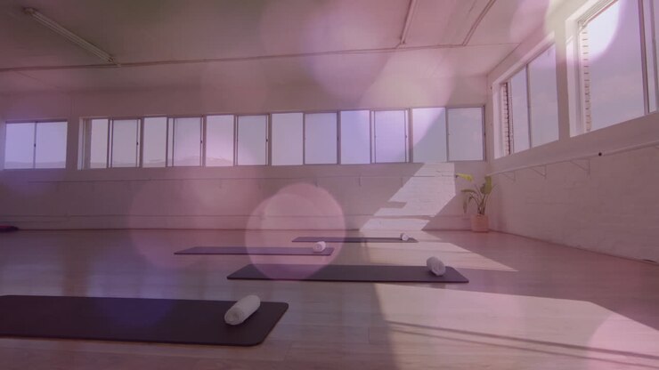 Tappetini da yoga e asciugamani in uno studio vuoto con animazione di luci bokeh.