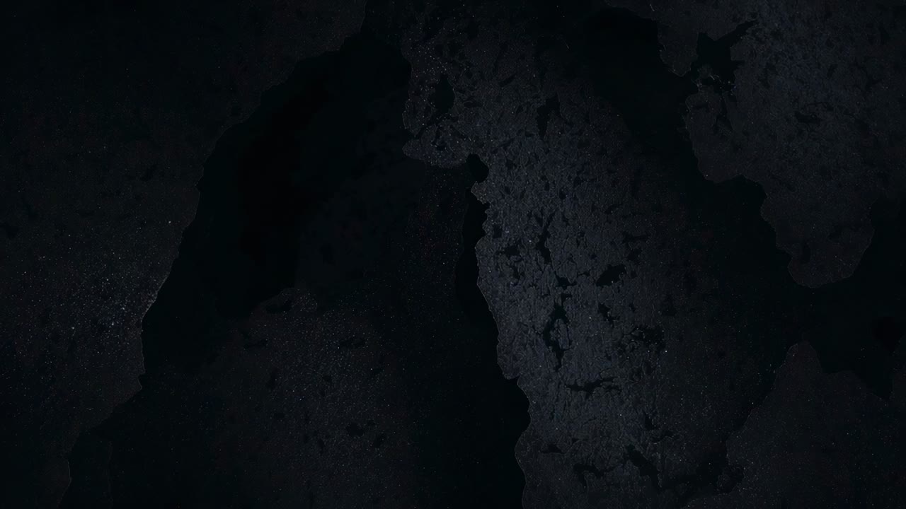 Camera shifting minimally at closeup, moving light across dark pitted surface for study