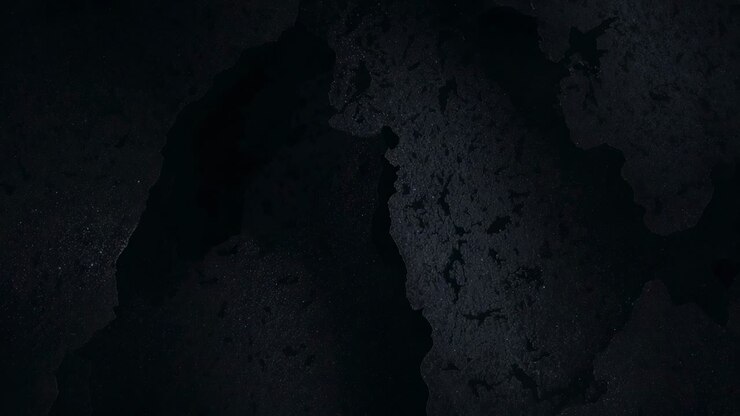 Camera shifting minimally at closeup, moving light across dark pitted surface for study