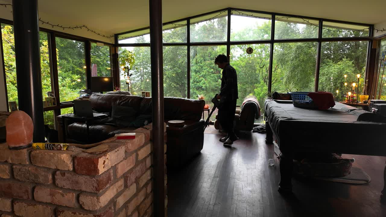man cleaning floor off-grid cabin in woods Wide shot