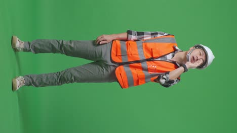 full body of asian male engineer with safety helmet yelling with hand over mouth while standing in the green screen background studio