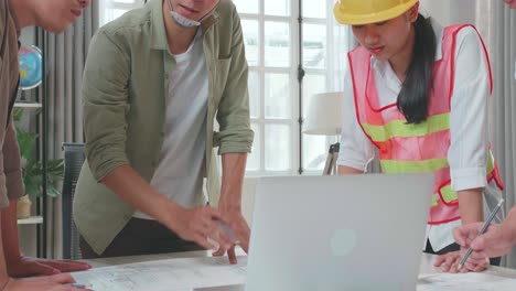 three asian engineers with helmets using laptop for working to a man at the office