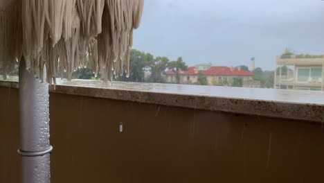 Las-Gotas-De-Lluvia-Caen-Sobre-El-Parapeto-Y-La-Sombrilla-Doblada-En-El-Balcón