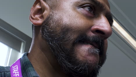 A-low-angled-close-up-shot-of-a-face-of-a-bearded-Asian-office-employee,-seated-while-working-in-front-of-his-computer