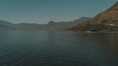 drone aéreo volando hacia un hombre en un bote en el lago de atitlán, guatemala