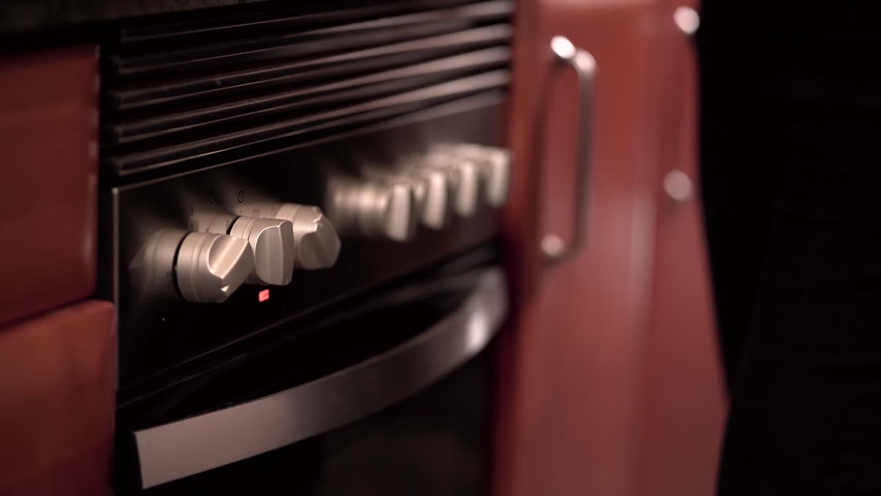 Person adjusting stove knobs in a modern kitchen