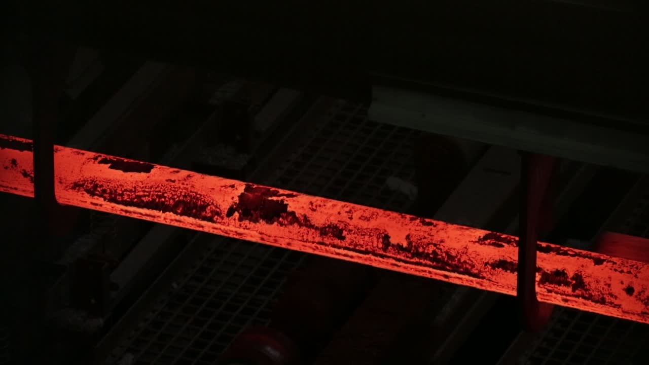 산업 환경에서 빛나는 뜨거운 강철 바, 어두운 배경, 질감과 열에 초점을 맞추십시오.