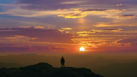 the man standing on a mountain top on a beautiful sunset background. time lapse