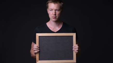 man holding empty blackboard while thinking