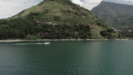 motorboat sails along coast of atitlan lake, guatemala