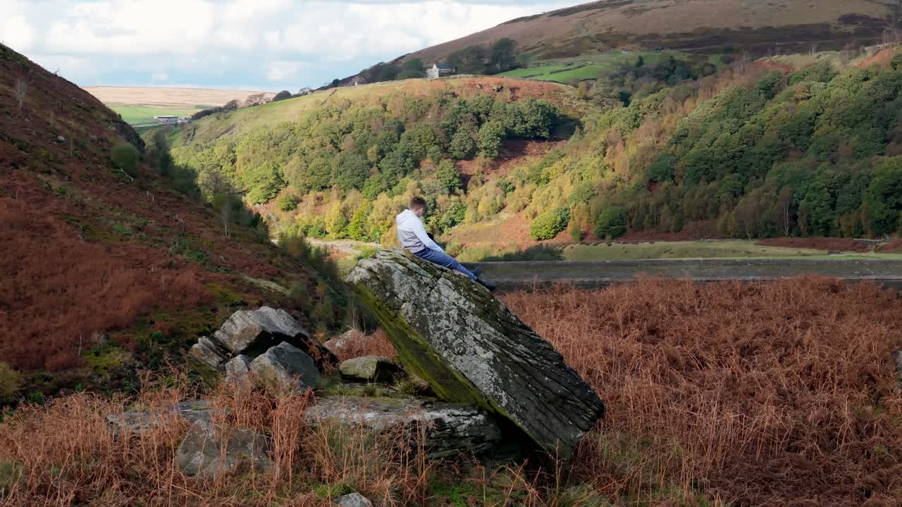 niño encaramado en una roca grande, contemplando profundamente