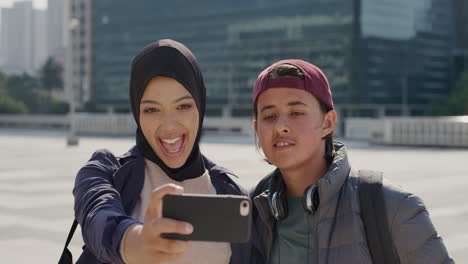 portrait-happy-multi-ethnic-friends-using-smartphone-taking-selfie-photo-making-faces-enjoying-warm-sunny-day-in-city-sharing-urban-travel-experience-on-mobile-phone-camera-technology-slow-motion