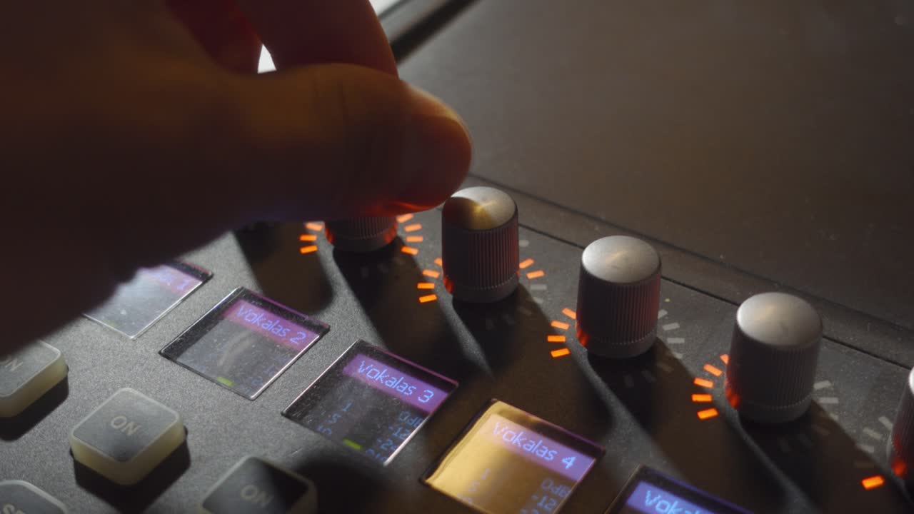 una persona girando algunas perillas en un mezclador de música